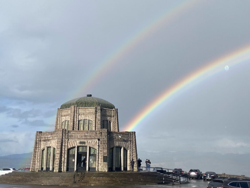 a perfect double rainbow ends in the dome-shaped vista house structure