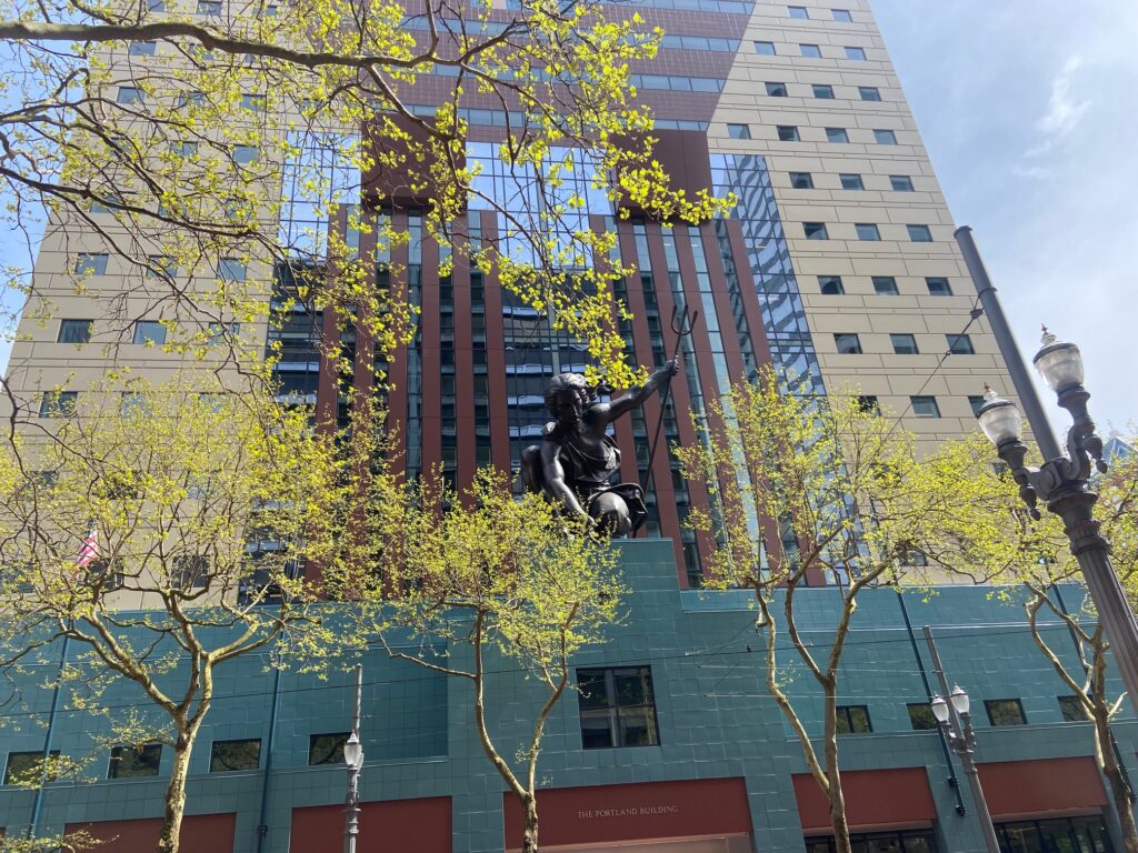an image of the statue that festoons the portland building - portlandia - with spring trees surrounding her